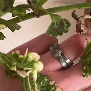 Bred äkta silverring med stenar - Säljer en bred ring i 925 sterling silver material med infattade stenar runt om. Ringen har en stilren och robust design och mäter cirka 21 mm i diameter. Perfekt för dig som gillar statement-smycken. Text på insidan av ringen. Lite repig på vissa ställen. 