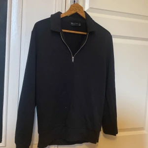 Svart tröja med dragkedja från ASOS DESIGN - Säljer en stilren svart half zip tröja från ASOS DESIGN. Tröjan har en dragkedja framtill och en klassisk krage. Perfekt för en avslappnad look. Priset går att diskutera. Skriv vid funderingar