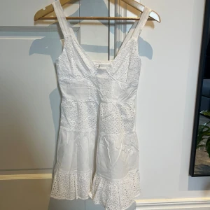 Vit klänning från Stradivarius - Söt vit klänning från Stradivarius med broderade detaljer och volangkant. Använd några få gånger. Passar super bra som studentklänning. Storlek XS.