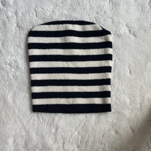 Randig stickad mössa - Snygg och stilren randig mössa i svart och vit. Perfekt för att hålla värmen under kyliga dagar. Den stickade designen ger en klassisk look som passar till många olika outfits.