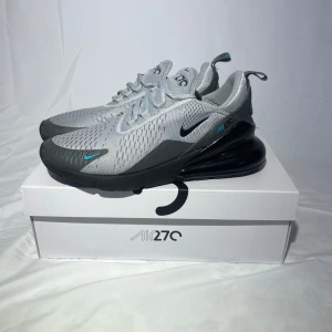 Nike Air Max 270 - Nike air Max 270 skor. Grå med blå detalj. Använda men väldigt fräscha och tvättade! Storlek 44,5 men ganska små i storleken, kan passa 43 och kanske en stor 42 med