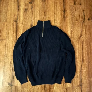 Svart ribbad tröja med dragkedja från Zara - Snygg svart ribbad tröja med dragkedja i halsen från Zara. Perfekt för kyligare dagar med sin stilrena design och bekväma passform. Ett måste i garderoben för en stilren look.