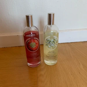 Body Mist från The Body Shop - Två flaskor body mist från The Body Shop. En med doft av jordgubbe i röd flaska och en med doft av moringa i genomskinlig flaska. Båda flaskorna rymmer 100 ml, det är ca hälften kvar  i den med jordgubbsdoft och två tredjedelar i den med moringa. Säljer båda för 50 kr tillsammans.