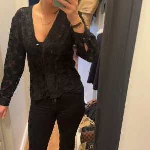 Svart spetsblus - Elegant svart spetsblus med v-ringning och knappar framtill. Blusen har långa ärmar med super fint mönster. Den är inte nopprig utan det är mönstret och den är endast använd någon enstaka gång. Perfekt till middagar eller lite finare tillfällen☀️🙌🏽köpt från Zara