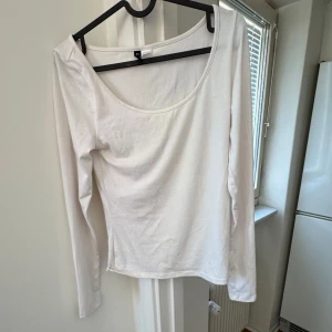 Vit långärmad topp från H&M - Säljer en stilren vit långärmad topp från H&M. Toppen har en rundad halsringning och är perfekt för en enkel och klassisk look. Passar bra till både jeans och kjol.
