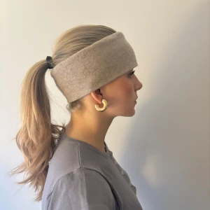 Beige kashmir pannband - Snyggt beige 100% kashmir pannband som håller dig varm och stilren. Perfekt för kyliga dagar och ger en elegant touch till din outfit. 