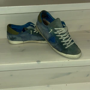 Blå och gröna sneakers med snörning - Snygga sneakers i en mix av blått och grönt med vita snören. Skorna har en rund tå och är tillverkade i ett material som ser ut som mocka. Perfekta för en avslappnad stil.