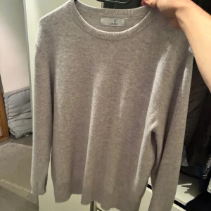 Grå tröja från Cashmasoft - Säljer en stilren grå tröja från Cashmasoft. Tröjan är långärmad och har en rund halsringning. Perfekt för kyligare dagar.
