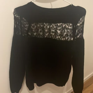 Svart spetsdetaljerad tröja från Trendyol - Säljer en elegant svart tröja från Trendyol med vackra spetsdetaljer över axlar och bröst. Tröjan har långa ärmar och en normal passform. Perfekt för att ge en stilren touch till din outfit. 🖤