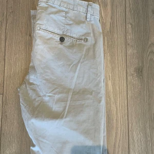 Beige chinos från Dondup - Snygga beige chinos från Dondup, tillverkade i Italien. De har en klassisk design med knapp och dragkedja framtill samt fickor både fram och bak. Perfekta för en stilren look.