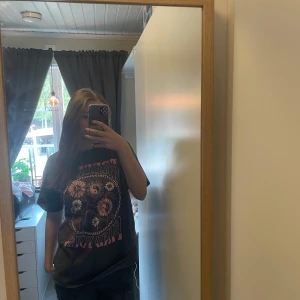 Grå t-shirt med tryck - Säljer en grå t-shirt med ett coolt tryck i rosa och vitt. Texten 'FREEDOM FIND YOUR' omger ett motiv av blommor och ett yin-yang-tecken. Perfekt för en avslappnad stil.