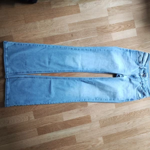 Ljusblå bootcut jeans från Nelly - Säljer ett par ljusblå bootcut jeans från Nelly. De har snygga röda broderade detaljer på bakfickorna och dubbla knappar fram. Perfekta för en avslappnad stil med en touch av retro.