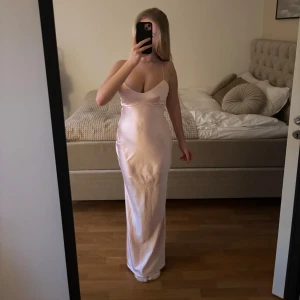 Ljusrosa balklänning av siden - Elegant ljusrosa balklänning i siden med smala axelband och så snygg öppen rygg som är lågt skuren med fin knytning. Brutalt snygg och endast avvänd en gång på min egen bal. Klänningen är uppsydd och är perfekt längd på mig som är 1,64 men går att sy upp mer eller borde gå att ta bort uppläggningen och förlänga. Storlek XS men passar mig som vanligtvis har S💞 Klänningen är köpt för 1700kr och är i helt nyskick. Perfekt till balen!! Pris kan diskuteras