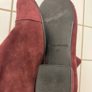 Röda mocka boots från Vagabond - Snygga röda boots i mocka från Vagabond. De har en elegant spetsig tå och en låg klack, perfekt för en stilren look. Passar utmärkt till både vardag och festliga tillfällen.