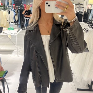 Svart läder/skinn jacka - Snygg svart läderjacka/skinnjacka med dragkedjedetaljer och en cool, tvättad look. Jackan har en oversized passform och långa ärmar. Svart/brun i färgen. Köpt för 799 och i nytt skick