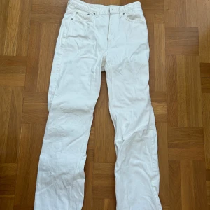 Vita jeansbyxor från Weekday - Snygga vita jeansbyxor från Weekday med en klassisk design. Byxorna har en normal passform och är perfekta för en stilren look. De har en dragkedja och knappar framtill.