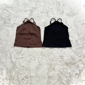 Två linnen i brunt och svart - Säljer två stilrena linnen i brunt och svart. Perfekta för sommardagar eller som basplagg i garderoben. De har smala axelband och en enkel design som gör dem lätta att matcha med olika outfits.