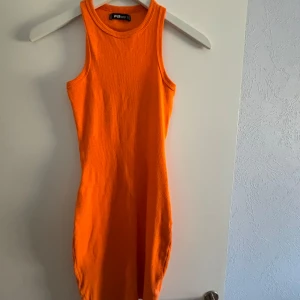 Orange ärmlös klänning  - Snygg och färgstark orange klänning. Den är ärmlös och har en tight passform som framhäver figuren. Perfekt för sommarens alla tillfällen. 🧡