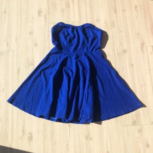 Blå axelbandslös klänning - Snygg blå axelbandslös klänning med en elegant och flödande kjol. Perfekt för sommarens fester eller en speciell kväll. Klänningen har en smickrande passform och är gjord i ett mjukt material som ger en bekväm känsla.