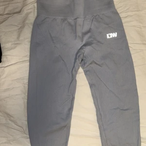 Grå tights från ICANIWILL - Snygga grå tights från ICANIWILL med hög midja och ribbad struktur. Perfekta för träning med en bekväm passform som ger bra stöd. Materialet är en blandning av nylon och spandex för optimal stretch och komfort.