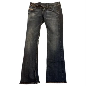 Diesel bootcut jeans blå, stl 29 - Snygga blå jeans från Diesel med bootcut passform och coola slitningar. Klassisk femficksmodell med dubbla knappar i midjan och kontrastsömmar. Tillverkade i Italien i mjukt denimtyg som sitter skönt hela dagen.
