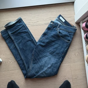 Mörkblå raka jeans - Snygga mörkblå jeans med klassisk femficksdesign och raka ben. Jeansen har orangea sömmar och en enkel look som passar till det mesta. Tillverkade i slitstarkt denimtyg för en tidlös vibe.