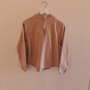 157 half zip - Mysig rosa hoodie från 157 i fleece, perfekt för kyliga dagar. Tröjan har huva, lång ärm med tumhål och half zip framtill. Tillverkad i 100% polyester och har en avslappnad passform. Enkel och stilren design som funkar till många outfits.