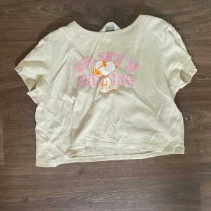 Gul snobben tröja  - Säljer en gul croppad t-shirt med tryck av Snobben och texten 'The sun is shining' i rosa. T-shirten har korta ärmar och är gjord i mjuk bomull. Perfekt för dig som gillar avslappnad och söt stil med en touch av nostalgi. 🌸