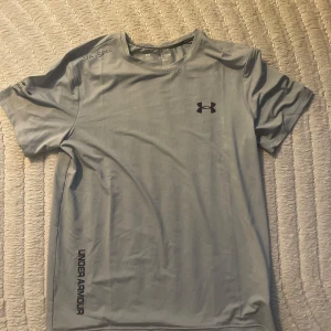 Under Armour sport-tshirt, flera färger - Säljer tre snygga Under Armour t-shirts i svart, ljusgrå och vit. Alla har åtsittande passform, rund hals och kort ärm. Materialet är mjukt och andas, perfekt för träning. Diskret logga på bröstet och tryck längs sidan. Riktigt clean och sportig vibe. 3 st för 400 kr/ 1 st för 150 kr