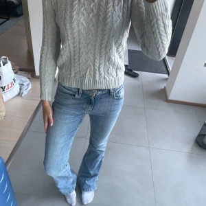 Ljusgrå stickad tröja från 157 - Säljer en ljusgrå stickad tröja från 157 med klassiskt flätmönster i mycket bra skick. Har använts som en varm och skön tröja i vardagen. 