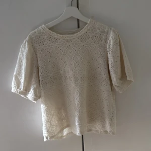 Vit spetsblus från Object, XL - Superfin vit blus från Object i storlek XL. Blusen har korta puffärmar och är helt täckt av broderad spets med snyggt mönster. Den är lätt transparent och har en rak passform, perfekt för dig som gillar romantiska detaljer och en luftig känsla.