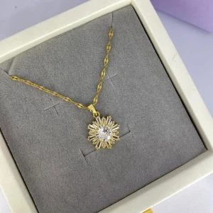 Guldigt halsband med gnistrande solhänge - Superfint halsband i guld med ett solformat hänge dekorerat med glittrande stenar. Kedjan är tvinnad och ger en lyxig känsla. Hänget har en rund mittsten omgiven av stavformade stenar som ger extra bling. Ej använd utan kommer från min small business. 