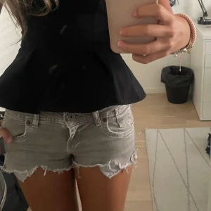 Low waist jeansshorts  - Snygga grå jeansshorts med låg midja och rå, fransig kant. Klassisk femficksmodell med knapp och dragkedja framtill. Perfekta för varma sommardagar och ger en avslappnad vibe. Passar dig som gillar en lite edgy och chill stil.