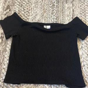 Svart ribbad offshoulder topp H&M Divided - Svart ribbad topp från H&M Divided med offshoulder-modell och korta ärmar. Snygg croppad passform. Storlek L men har själv storlek S och tycker den sitter fint.