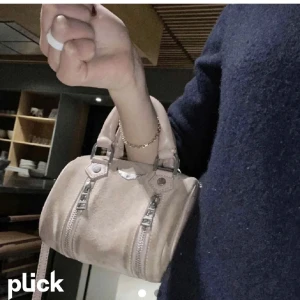Rosa väska från Zadig & Voltaire! - Supersöt rosa handväska från Zadig & Voltaire i mocka med två silverfärgade dragkedjor framtill och ett ikoniskt vingemblem. Väskan har både handtag och axelrem så du kan bära den på flera sätt. Perfekt storlek för det viktigaste och ger en cool vibe till din outfit. Enda defekten är att mockan är lite smutsig, men det går att lösa hur enkelt som helst med mockatvätt. 🥰