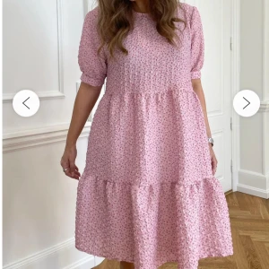 Rosa blommig volangklänning - Supersöt rosa klänning med småblommigt mönster och volangkant. Modellen är lös och har puffiga korta ärmar samt rund halsringning. 