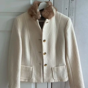 Vintage kappa från Max Mara Weekend - Snygg beige kappa från Max Mara Weekend Italien med pälsdetalj på kragen och guldiga knappar framtill. Jackan har två fickor och är fodrad med mönstrat tyg. Köptes av min mamma för nagra är sen men är inte min stil. Jackan är knappt använt och ser ut som helt ny, perfekt till hösten. Nypris 12k 