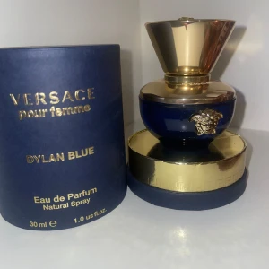 Versace Dylan Blue Pour Femme EdP 30ml - Lyxig parfym från Versace, Dylan Blue Pour Femme, 30 ml Eau de Parfum. Flaskan är djupblå med gulddetaljer och Versaces ikoniska Medusa-emblem framtill. Kommer i elegant rund förpackning i blått och guld. Perfekt för dig som gillar exklusiva dofter.