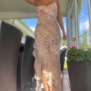 Leopardmönstrad långklänning med volang - Säljer en snygg långklänning med leopardmönster i beige och bruna toner. Storlek L men skulle säga att den passar även för någon som har s eller m.