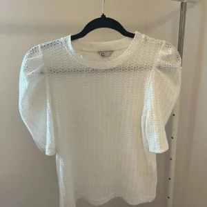 Vit blus med puffärm och hålmönster - Säljer en vit blus från Cubus med snygga puffärmar och hålmönstrad struktur. 