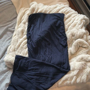 Marinblå långkjol från Gina Tricot - Säljer en marinblå långkjol (går att använda som tight klänning) från Gina Tricot. Klänningen har en tight passform med rynkade detaljer längs sidorna och är tillverkad i mjuk bomull. Perfekt för dig som gillar en stilren och enkel look. Det ser skrynklig ut på bilden men är enkel att stryka vilken kan göras innan paketet skickas