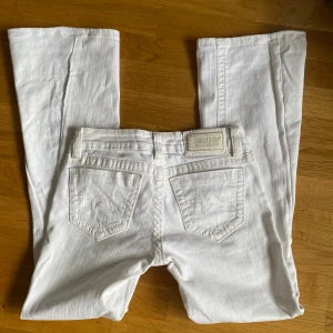 Vita jeansbyxor från Miss Me - Säljer ett par vita jeans från Miss Me som är omsydda till utsvängda jenas.  Fickorna har broderade detalijer i beige. Perfekta för dig som vill ha ett par stilrena och snygga jeans.