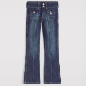 Mörkblå bootcut jeans med fickor - Snygga mörkblå jeans med bootcut passform och två framfickor med lock och knappar. Jeansen har dubbla knappar i midjan och klassisk jeanslook med lätt slitning.