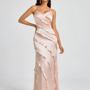 Långklänning i satin med volangdetaljer - Säljer min helt nya balklänning i satin med smala axelband och v-ringning. Klänningen har diagonala volangdetaljer i en ljusgul färg. Perfekt för bal eller festliga tillfällen!💕