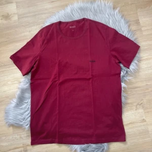 Röd t-shirt från BOSS - Säljer en röd t-shirt från BOSS i storlek XXL. T-shirten har rund halsringning, korta ärmar och en liten BOSS-logga på bröstet. Tillverkad i mjuk bomull för en skön känsla. Perfekt för en avslappnad stil.
