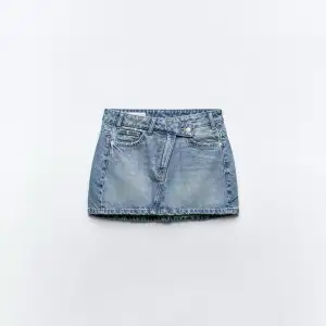 Säljer en klassisk blå jeanskjol från Zara med femficksmodell och bälteshällor. Kjolen är kort och har en rak passform, perfekt till sommaren. Stängs med knapp och dragkedja framtill.