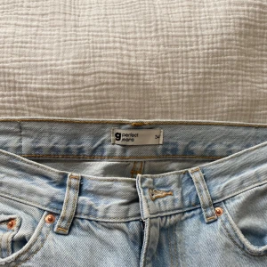 Ljusblå jeansbyxor från Gina Tricot - Säljer ett par ljusblå jeansbyxor från Gina Tricot i klassisk femficksmodell. Byxorna har normal passform, raka ben och är tillverkade i denim med synliga kopparfärgade nitar och knapp. Perfekta för en avslappnad stil.