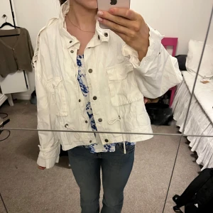 Vit vårjacka - Säljer en vit vårjacka med två fickor och en del smådetaljer. Jackan har justerbart bälte i midjan för att man själv ska kunna justera hur man vill att den ska sitta💕Skitsnygg till sommaren. Strl S men skull även säga att den passar Xs/M