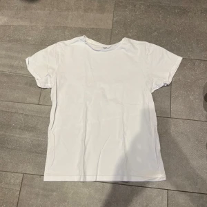 Vit t-shirt - En basic vit t-shirt med rund hals och korta ärmar. Perfekt att matcha med jeans eller shorts för en clean och enkel stil.