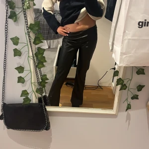 Svarta skinnbyxor - Säljer ett par svarta skinnbyxor från Kappahl. Byxorna är mid waist/low waist och bootcut. Perfekta för en trendig look och lätta att matcha med olika toppar. Köpte i Januari och har aldrig använt 💞Dom är så snygga och passar till det mesta❤️ Säljer då dom har blivit för korta för mig, jag är ca 165 som referens💞
